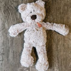 a white teddy bear laying on top of a wooden floor