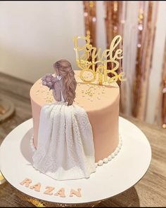 a pink and gold wedding cake with a bride on top