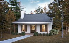 a small white house sitting in the middle of a field next to trees and grass