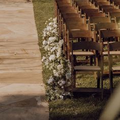 rows of wooden chairs with white flowers on the grass and in front of them are empty