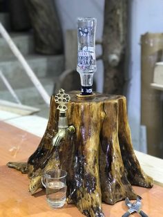 a wooden table topped with a glass filled with water next to a bottle opener and corkscrew