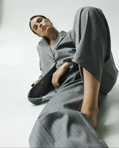 a man laying on the ground wearing a suit and tie with his hands in his pockets