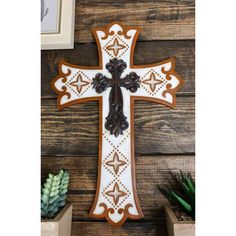 a wooden cross hanging on the wall next to succulents and other items