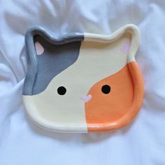 a ceramic cat shaped dish on a white sheet