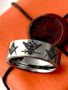 Celebrate his accomplishments with this stunning 33 Degree Masons Two Headed Eagle Tungsten Wedding Ring, Like the square and compasses symbol, the double-headed eagle motif is one of 33º Scottish Rite Freemasonry's most recognizable symbols. Stunning and detailed this Masonic Tungsten Ring is durable and fashionable. The inside shank is rounded for Comfort fit. If you like the design, but prefer the ring in Silver, Yellow gold or Rose gold color, please contact me to check the size and availabi Symbolic White Gold Signet Ring For Wedding, Symbolic Stainless Steel Jewelry For Wedding, Rectangular Wedding Ring With Polished Finish, Custom Hallmarked Signet Ring For Wedding, Custom Wedding Signet Ring Hallmarked, Stainless Steel Rings With Engraving Option For Wedding, Stainless Steel Wedding Rings With Engraving Option, Wedding Rings With Engraving Option In Stainless Steel, Compass Symbol