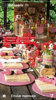 the table is set with red and white placemats, napkins, wine glasses, and flowers