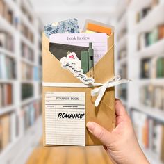 a person holding up a book in front of a library filled with books and papers