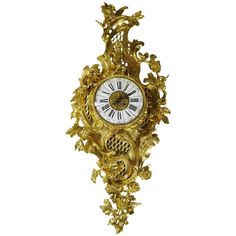 an ornate gold clock with roman numerals and flowers on the face is shown against a white background