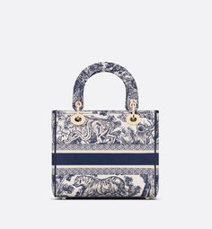 The Lady D-Lite bag combines classic elegance with House modernity. The style is fully embroidered with the blue Toile de Jouy motif. The front features a Christian Dior Paris signature while the thick D.I.O.R. charms in pale gold-finish metal enhance the silhouette. Equipped with a wide, reversible and removable embroidered shoulder strap, the medium Lady D-Lite bag can be carried by hand or worn crossbody.. Luxury Tote Bag With Embroidered Logo, Luxury Bags With Embroidered Logo For Daily Use, Luxury Shoulder Bag With Embroidered Logo For Daily Use, Luxury Double Handle Shoulder Bag With Embroidered Logo, Luxury Shoulder Bag With Embroidered Logo And Top Handle, Elegant Top Handle Shoulder Bag With Embroidered Logo, Luxury Blue Bag With Embroidered Logo, Classic Bags With Embroidered Logo For Daily Use, Classic Rectangular Bags With Embroidered Logo