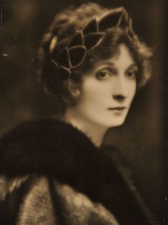 an old black and white photo of a woman wearing a fur coat with a large collar