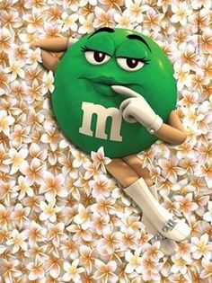 a green ball with the letter m on it sitting in front of white and yellow flowers