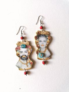 Earrings depicting two subjects of the most famous Caltagirone ceramics. Made of thickened paper with a wood texture. Beads made of red turquoise paste. Sizeable but extremely light, with golden glitter profiles and Murrina beads decorations. These jewels are brightest and will surely give your summer outfits a Mediterranean look. These earrings have been strictly hand made and can be reproduced in a limited number of pieces with similar characteristics. The artisanal crafting makes any jewel a Caltagirone Ceramics, Fiber Jewelry, Golden Glitter, Face Earrings, Red Turquoise, Wood Texture, Jewelry Creation, How To Make Beads, Handmade Earrings