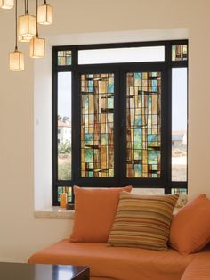 a living room filled with furniture next to a window covered in stained glass panels and pillows