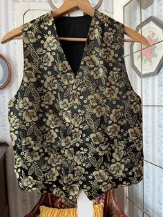 This fancy vest is made from a polyester blend in black, with an overall pattern of flowers and leaves in shiny metallic gold. It has the original buttons and two front pockets, and it's fully lined with black silky lining. The back matches the lining. The measurements, taken with the vest lying flat, are: shoulder to shoulder, 12 inches; armpit to armpit, 18 inches; length, 24  inches in front and 20 1/2 inches in back; bottom edge, 17 1/2 inches. In very good condition. Fancy Vest, Gold Vest, Dark Wedding Theme, Homecoming Ideas, Dark Wedding, Vest Waistcoat, Black Vest, Vest Outfits, Outfit Style