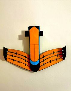 an origami model of a plane on the side of a white wall,