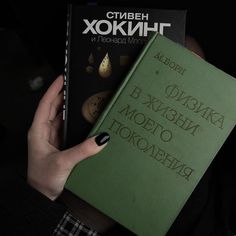 a person holding two books in their hands, one is green and the other is black