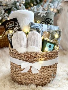 a basket filled with lots of items on top of a white rug next to a christmas tree