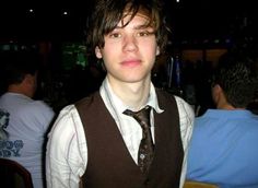 a young man wearing a brown vest and tie