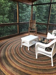 two chairs and a table on a porch with a rug in the middle that looks like a circle