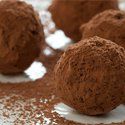 chocolate truffles on a white plate with sprinkles and powdered sugar