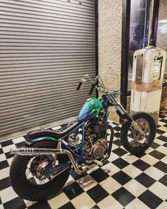 a green and black motorcycle parked in front of a garage door on a checkered floor