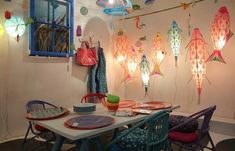 a dining room table and chairs with colorful decorations on the wall behind it, along with hanging lights