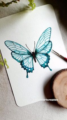 a blue butterfly is sitting on top of a piece of paper next to a wood slice