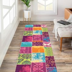 a brightly colored area rug in the middle of a room with a chair and potted plant