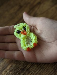 a hand holding a yellow and orange ring with a bird on it's face