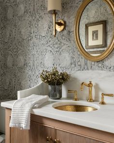 a bathroom with a sink, mirror and gold faucet