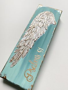 a wooden sign with an angel's wing painted on it