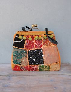 This bag is the real deal, 100% guarantee on many many WOW's! We have made this amazing bag with vintage sari embroidery, embroidered by hand with lots of seed beads and sequins, during the times that there was no TV to keep people occupied. The embroidery is from the far east, Asia. The patches of treasures with smashing colors gives this bag something very exotic. The bag closes with a wonderful brass snap closure (kiss-lock) with a satin finish and stands on it's own. It has leather (upcycled Vintage Bags For Festivals, Vintage Embroidered Festive Bags, Bollywood Style Rectangular Bags With Zari Work, Traditional Orange Bag For Daily Use, Multicolor Vintage Shoulder Bag For Festivals, Vintage Multicolor Bags For Festivals, Traditional Orange Shoulder Bag For Travel, Traditional Orange Pouch Bag, Bohemian Multicolor Bags With Zari Work