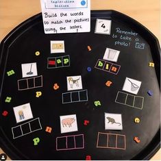 a black tray with pictures and words on it that are written in different colors, shapes and sizes