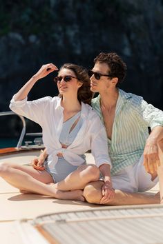 a man and woman are sitting on the back of a boat, posing for a photo