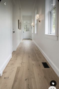 an empty hallway with wood floors and white walls