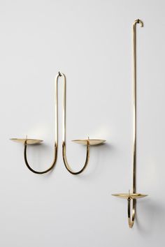 two brass - plated hooks hang on the wall, one holding an umbrella hook