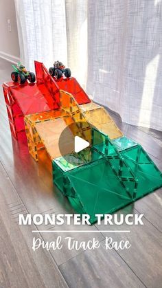 three lego monster trucks sitting on top of a wooden floor in front of a window