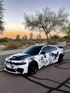 a white and black camo car parked on the street