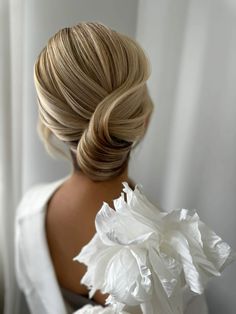 the back of a woman's head with white flowers in her hair and dress