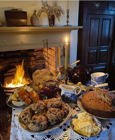 a table topped with cakes and pies next to a fireplace