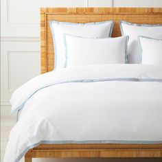 a bed with white sheets and blue trim