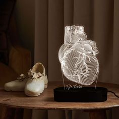 a heart shaped lamp sitting on top of a wooden table next to a pair of shoes