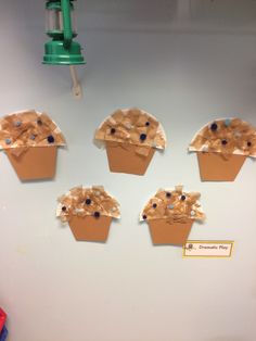 four cupcakes made out of brown paper on a white board with blue dots