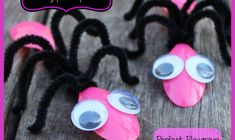 some pink and black spider decorations on a wooden table