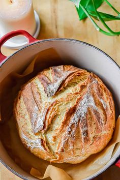 a loaf of bread sitting in a pan on top of a wooden table next to a glass of milk