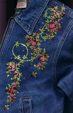 an embroidered denim jacket with pink flowers on it