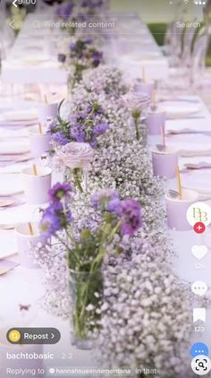 a long table with purple and white flowers in vases next to eachother