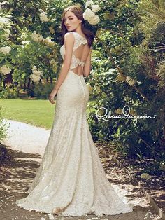 a woman in a wedding dress standing on a path surrounded by trees and white roses