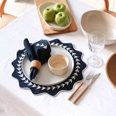 a white table topped with plates and bowls filled with apples