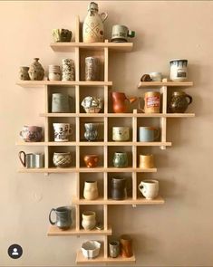 a wall shelf filled with lots of cups and mugs on top of wooden shelves